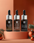 Three Eminence serums on display with holiday ornaments