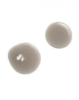 Two round beige beads, one with a small hole, likely part of a skincare or cosmetic product, used for application or formulation