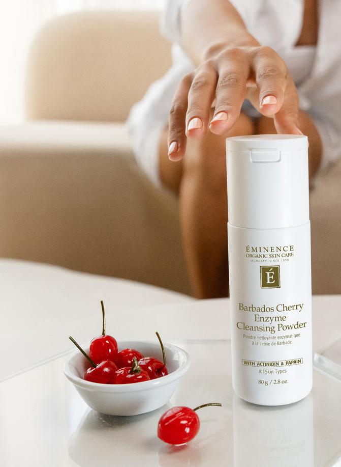 Hand reaching for Eminence Cherry Enzyme Cleanser with cherries