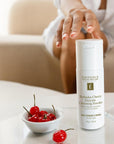 Hand reaching for Eminence Cherry Enzyme Cleanser with cherries